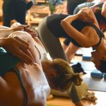 Gruppe von Menschen in Yoga-Position nach vorne übergebeugt