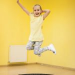 Kind, das in Turnhalle von Trampolin hochspringt