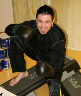 Trainer Maik mit Boxhandschuhen auf Trainingsbank in Hocke